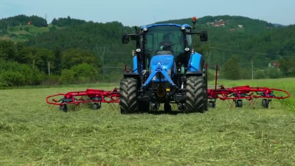 Egy Farmer Egy Nagy Kék Traktorban Piros Mezőgazdasági Gépeket Húz — Stock videók