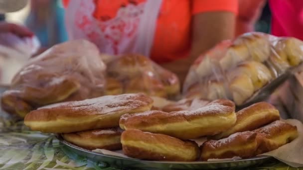 Domzale Slovenia 2018年6月テーブルには揚げたてのおいしいドーナツが展示されています 白砂糖を振りかける人もいます — ストック動画