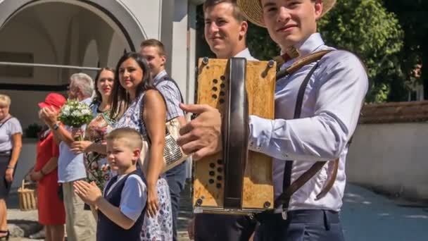 Domzale Slovenia 2018年7月一位音乐家将在婚礼上演奏手风琴 婚礼的来宾们正在等待一对已婚夫妇从教堂出来 — 图库视频影像