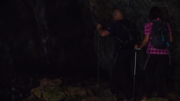 カップルは洞窟の中でハイキングしていて 彼らは洞窟から出ようとしています 外には美しい自然があります — ストック動画