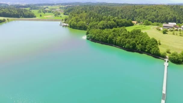 スロベニアの真ん中にある大きな青い湖 橋は一つの側面から別の側面へ向かっています その日は素晴らしいと日当たりの良い 空中射撃 — ストック動画