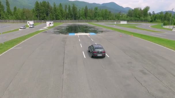 一辆黑色汽车在一个安全驾驶中心的一条滑路上行驶 它开始向左和向右移动 空中射击 — 图库视频影像