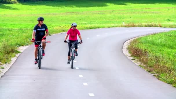 Δύο Άνθρωποι Κάνουν Ποδήλατο Στο Δρόμο Και Ελέγχουν Ένα Αυτοκίνητο — Αρχείο Βίντεο