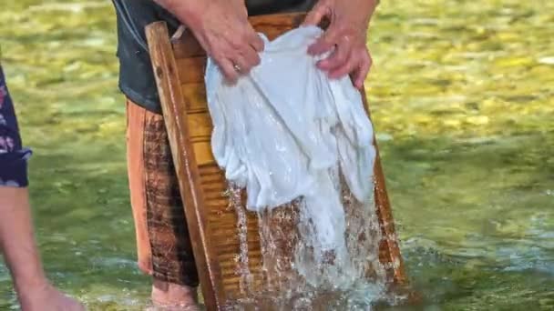 年配の女性が水の中の板に白いシャツを洗っている 彼女はまた いくつかのヴィンテージで 古い服を着ている — ストック動画