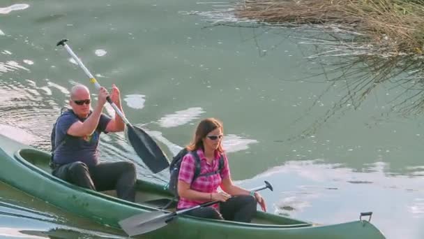 男と女がカヌーの中でゆっくりと漕いでいると 彼らは止まっている 川での平和な一日だ — ストック動画