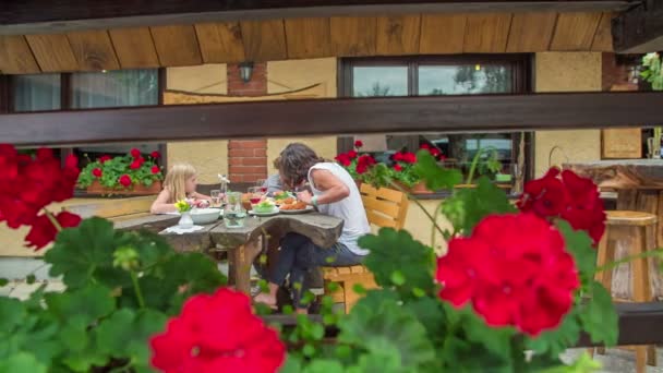 가족이 밖에서 식당에서 점심을 있습니다 아름다운 꽃들도 피어나고 있습니다 — 비디오