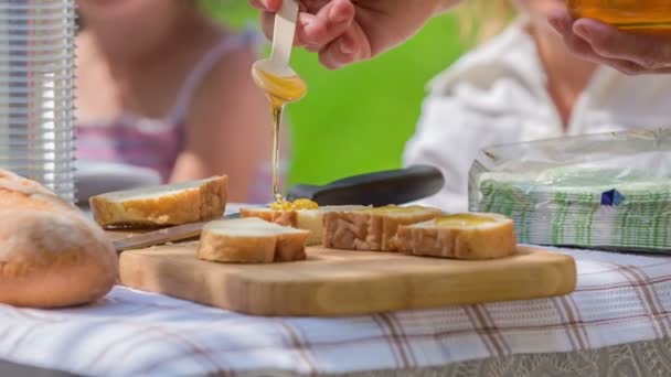 Ein Lehrer Legt Langsam Honig Auf Ein Paar Brotstücke Die — Stockvideo