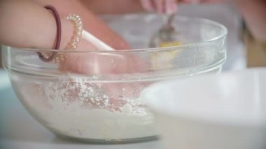 Aşçılık sınıfındaki öğrencilerden biri hamuru yoğuruyor. Diğer öğrenciler ona yardım ediyor..
