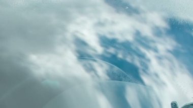 Biri arabanın camlarını temizliyor. Güvenlik eldiveni takıyor ve temizlik sıvısı ve bez kullanıyor..