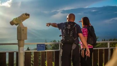 Manzara harika. Bir çift tepenin üstünde duruyor ve bir adam vadideki ortağına bir şey gösteriyor..