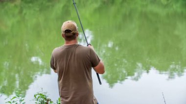 Bir balıkçı göl kenarında balık tutuyor. Orada sabırla balık oltasını yakalamak için bekliyor..