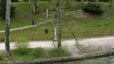 İnsanlar nehrin yanındaki bir yolda yokuş yukarı yürüyorlar. Sakin bir sonbahar günü ve dışarıda hiç güneş ışığı yok..