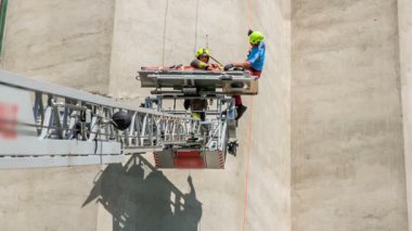 Kurtarma ekibinden iki kişi kendine zarar veren birinin sağ salim yere inmesini sağlıyor..