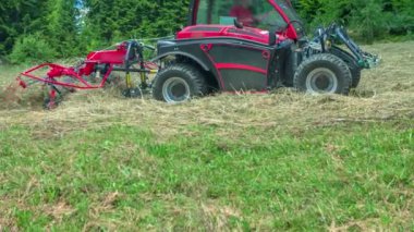 Tepede küçük bir traktör saman hazırlıyor. Hava güneşli ve sıcak..