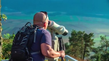Bir adam dürbünle manzarayı izliyor. Güzel ve güneşli bir gün..