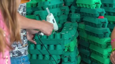 Okuldaki genç bir çocuk yeşil yumurta kutularına yapıştırıcı sürüyor. Sanat dersinde bir şeyler yapıyorlar..