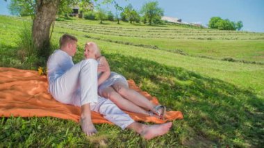 Genç bir çift bir ağacın altında bir battaniyenin üzerinde uzanıyor ve birbirlerinin gözlerinin içine bakıyorlar. Yaz mevsimindeyiz ve birbirlerine deliler gibi aşıklar..