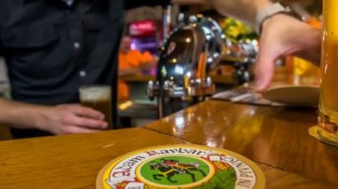 DOMZALE, SLOVENIA - 16. HAZİRAN 2018 Bir barmen bir müşterinin önüne bier minder koyar.