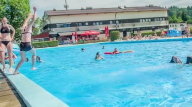 DOMZALE, SLOVENIA - 20. Haziran 2015 'te bir kız başka bir kızı yüzme havuzuna itti. Gençler havuz başında eğleniyor..