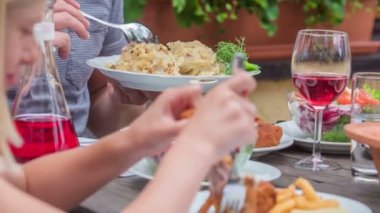 Genç bir aile birlikte lezzetli bir öğle yemeği yemekten zevk alıyor. Kızarmış tavuk, patates, salata, içme suyu ve kırmızı şarap içiyorlar..