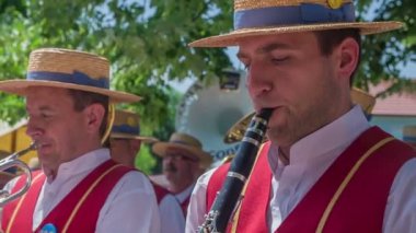 İki yaşlı adam bir bandoda müzik enstrümanları çalıyor. Hasır şapka festivalinde sahne alıyorlar..
