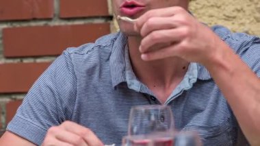 Genç baba tavuk budu yiyor ve sonra parmaklarını yalıyor. Genç bir aile öğle yemeğinin tadını çıkarıyor..