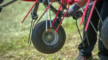 Genç bir çiftçi, tarım makinelerinin lastiklerinin sağlam olduğundan emin oluyor. Güvenlik eldiveni giyiyor..