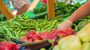 Bu büfede güzel taze sebzeler sergileniyor. Yeşil fasulye, kırmızı domates ve sarı biber görebiliyoruz..