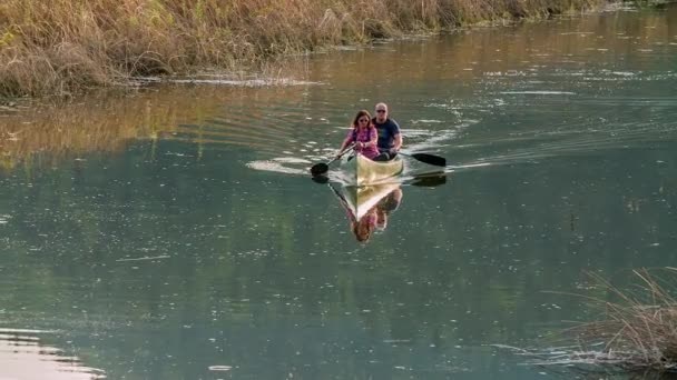 夫婦が川を漕いでいる 彼らはカヌーに乗っている 川は少し汚れて見える — ストック動画