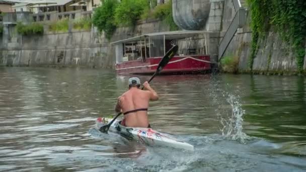 若い男がリュブリャナ川をカヤックで渡っている 彼は本当に速くやっている — ストック動画