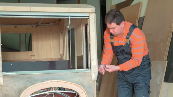 参加者は 製造中の木製の車の上にいくつかのネジを巻き上げています 自宅の工房で何か新しいものを作っている — ストック動画