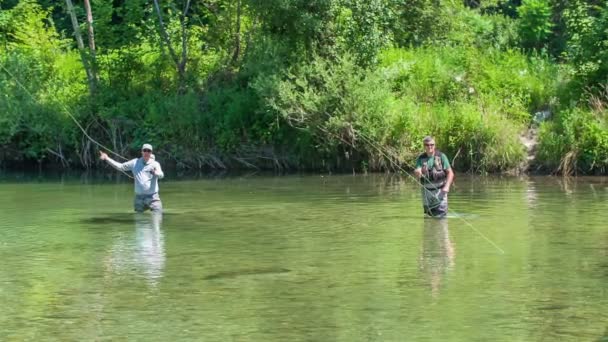 2人の漁師が水の中に立って釣りをしている 自然は緑で美しく見えます — ストック動画