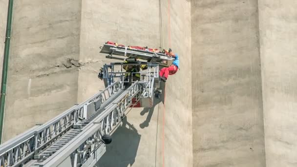 两名具有攀爬技巧的消防员正在营救一名爬上墙壁时受伤的人 他们要把他放在消防车的梯子上 — 图库视频影像