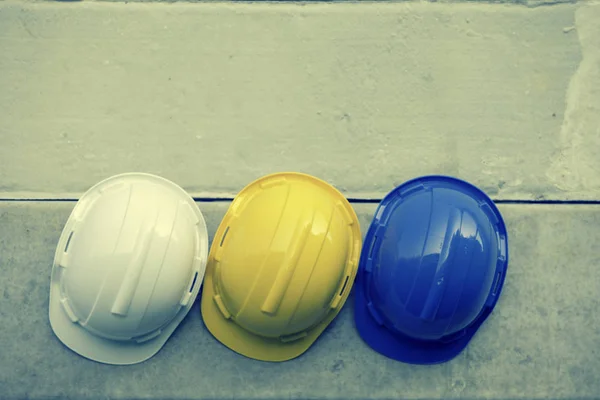 Safety helmet Blue, Yellow, White On the concrete wall,Hats for engineering and construction hang on the cement wall.safety helmet On the concrete