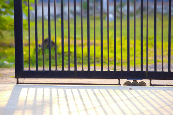A gate of a house in the morning,fence iron, metal fence,shadows of metal fence,Metal black gate