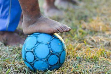 Yakın çekim üzerinde futbol oynarken kirli ayaklar, Barefoot çocuk oyun futbol eski, Asya çocuk oynarken eski futbol