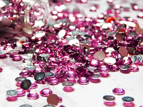大理石のテーブルの上のガラス瓶から注がれたピンクのラインストーン — ストック写真