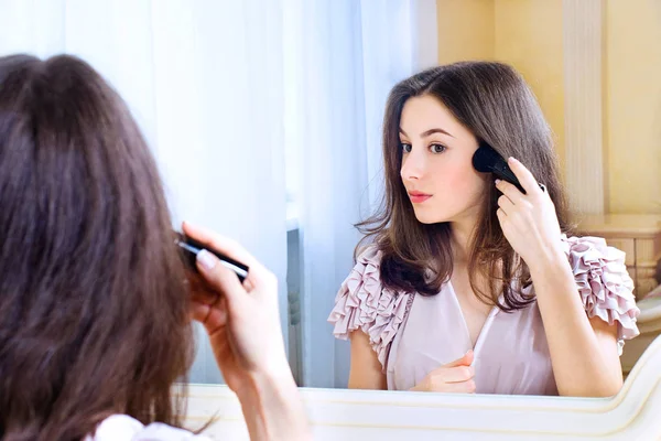 Portrait of  beautiful young woman looking at the mirror