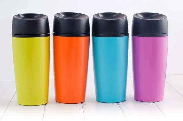 Tasses thermos couleur sur la table en bois blanc — Photo