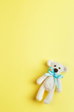 Turkuaz düğümlü ayı oyuncağı sarı arka planda polisle