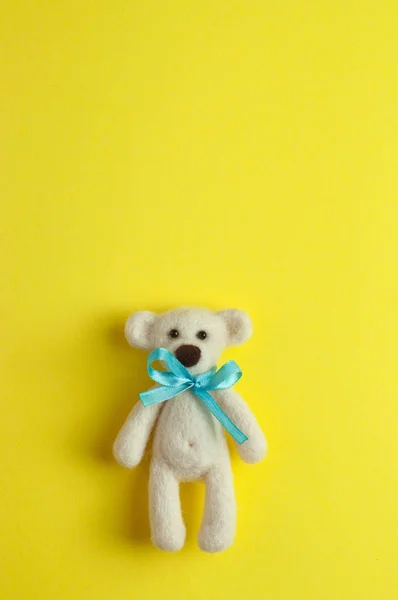 Bear toy with turquoise bow-knot over yellow background with cop — Stock Photo, Image