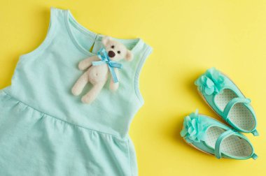 Küçük kız için elbise ve ayakkabılar ve ayı oyuncağı sarı kuyruk sokumuna.