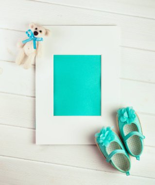 Çerçeve, ayı oyuncağı ve küçük kız için ayakkabılar.