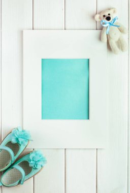 Çerçeve, ayı oyuncağı ve küçük kız için ayakkabılar.