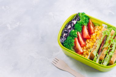 Beton sırt üstü sandviç ve sebzelerle dolu beslenme çantası.