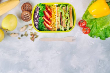 Gri betondan yapılmış sandviç ve sebzelerle dolu beslenme çantası.