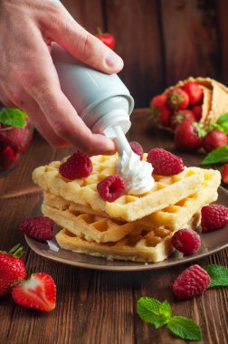 Erkekler Belçika waffle 'ına krem şanti sürüyor.