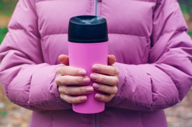 Elinde termosu olan bir kadın dışarıda yürüyor.