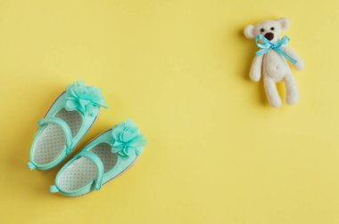 Ayı oyuncağı ve bebek için turkuaz ayakkabılı sarı bebek arkaplanı