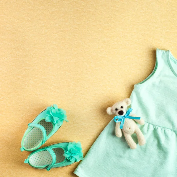 Jurk en schoenen voor baby meisje en beer speelgoed over beige achtergrond — Stockfoto